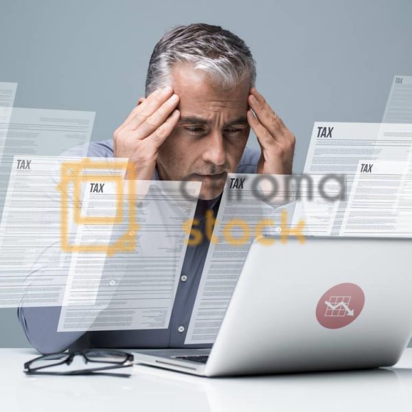 Pensive businessman checking tax forms online using a laptop: finance, taxation and costs concept